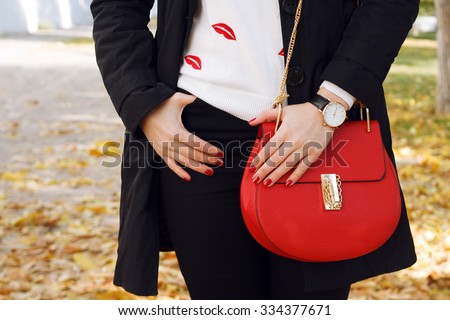Fashion girl wearing coat ,red handbag, black jeans ,white pullover. Trendy accessories