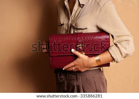 Woman fashionable girl wearing silk blouse holding red leather bag handbag in hand. Stylish accessories