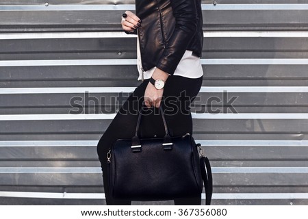 Young stylish woman in black trendy outfit with big bag in hand street look