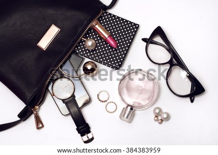 Fashionable female accessories watch glasses lipstick perfume and black bag. Overhead of essentials for modern young woman.