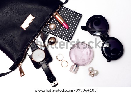 Top view of female accessories for woman. Trendy black sunglasses, black handbag , watch , lipstick , perfume , rings , smart phone