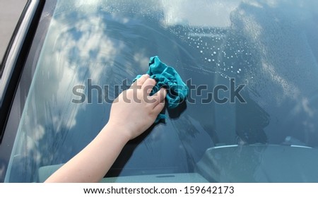 Boy cleans the window of a car