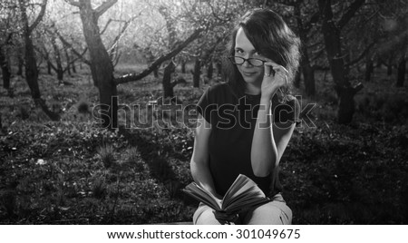 Black and White. Woman in park outdoor with tablet and paper book deciding what to use