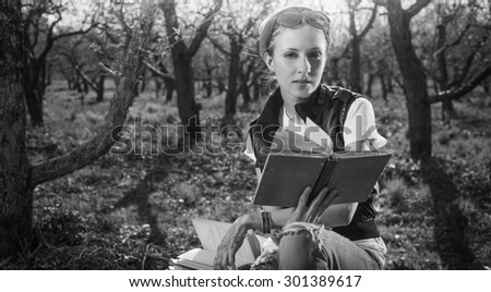 Black and White, BW. Woman in park outdoor with tablet and paper book deciding what to use