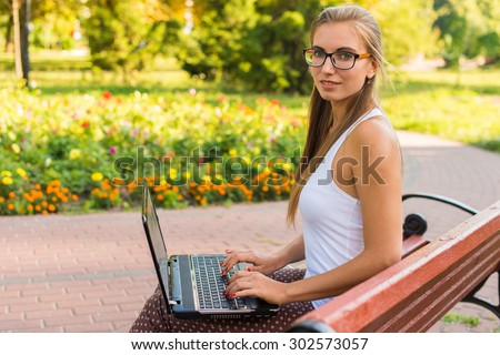 Young woman using tablet, laptop, notebook, reading books outdoor, smiling.