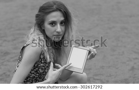 Black and White. Young woman using tablet outdoor, smiling.