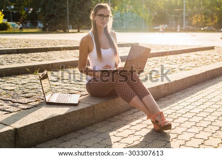 Serious woman watching a laptop in a restaurant terrace with an unfocused background