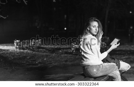 Black and white. Young woman sitting with Tablet and reading from ebook