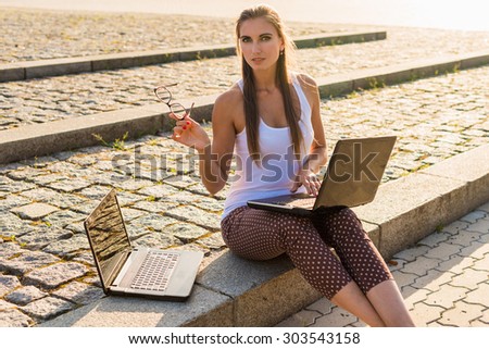 Student woman watching a laptop outdoor in city with an unfocused background