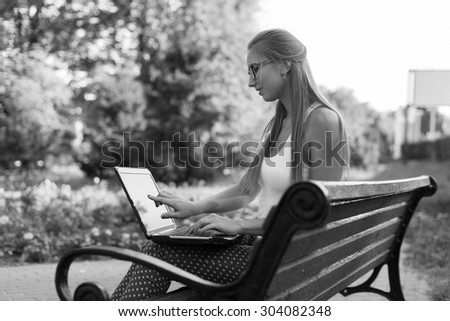 Black and White. BW. Young woman using tablet, laptop, notebook, reading books outdoor, smiling.