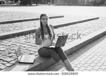 Black and White. BW. Student sitting in park near the grass working on laptop at campus