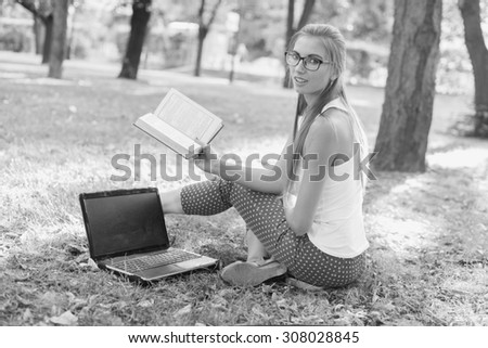 Black and White. BW. Student sitting in park near the grass working on laptop at campus