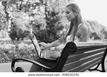 Black and White. BW. Portrait. Student sitting in park near the grass working on laptop at campus