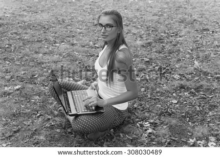 Black and White. BW. Portrait. Student sitting in park near the grass working on laptop at campus