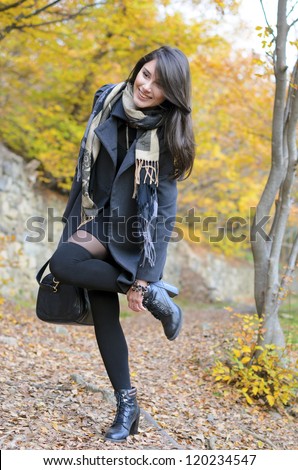 Happy woman, adjusting her shoes in the autumn park