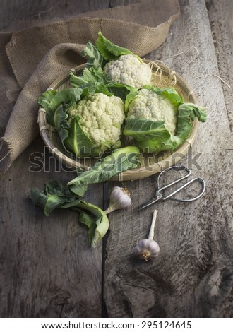 Organic cauliflowers in basket on rustic wooden table top. Top view.