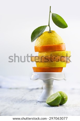 Stack sliced citrus fruits display on a white high plate. Food styling.