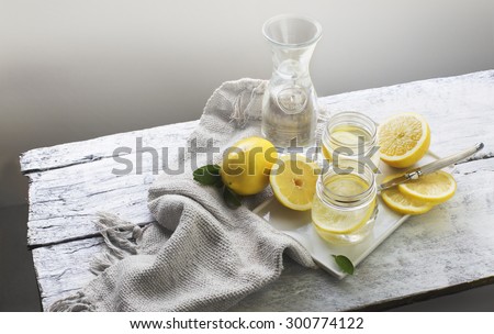 Lemon and soda water with lemon slice in vintage drinking glass. Vertical arrangement food styling. Summer party table shot.