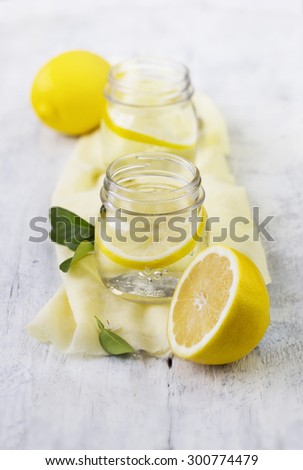 Soda water with lemon slice in vintage drinking glass. Vertical arrangement food styling. Summer party table shot.