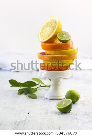 Various sliced citrus fruits on white cupcake stand. White wooden vintage background. Close-up table top shot. Still life. Food styling.
