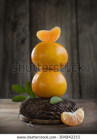 Mandarin oranges and peels on moody rustic wooden table top. Food still life. Eye-level view. Close-up.