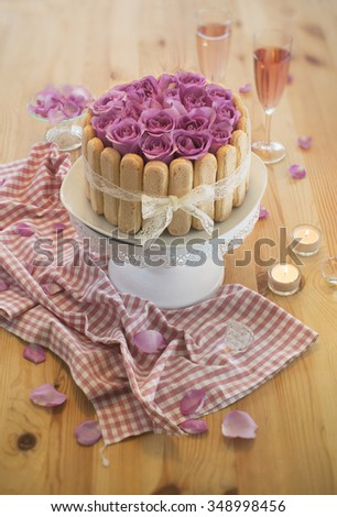 Wedding anniversary or birthday cake on wooden table top with two glasses sparkling wine. Warm moody lighting. Closeup.