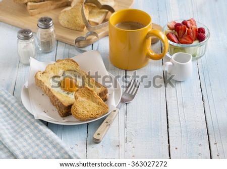 Heart shaped sunny side up egg with toast on light blue wooden breakfast table top. Valentine\'s day morning romantic breakfast.