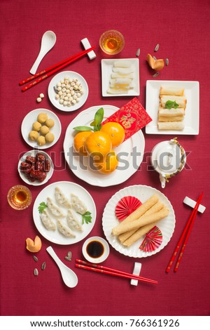 Flat lay Chinese new year food and drink, reunion dinner food still life on red table top background. Translations of text appear in image: Prosperity.