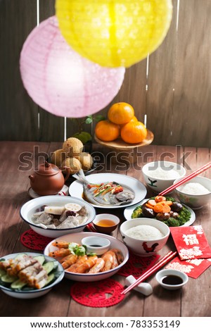 Text appear in image: Prosperity. Chinese new year reunion dinner food and drink on wooden table top.