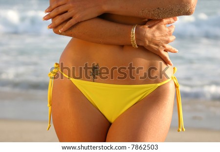 stock photo Midriff of a Woman in a Yellow Bikini with a Rose Tattoo on