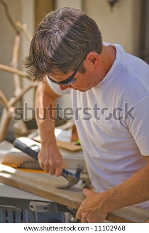 Man using a Hammer to pull a nail out of wood