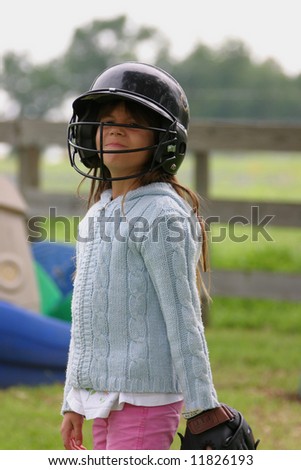 Pretty little Girl wearing Baseball Gear outdoors