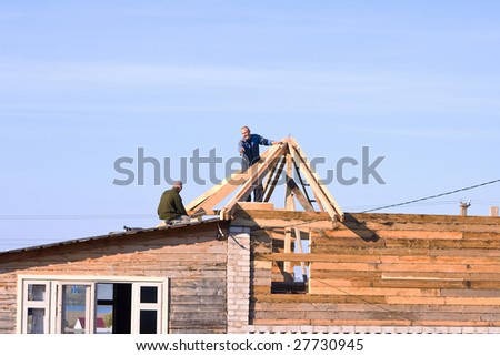 Two workers on not complete construction of the private house against the blue sky