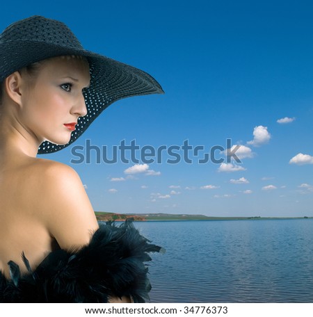 serenity women in black hat and boa against summer landscape with quiet water of lake