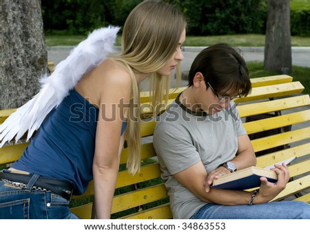 A young men reading a book in a summer park. Guardian Angel is sitting next to him