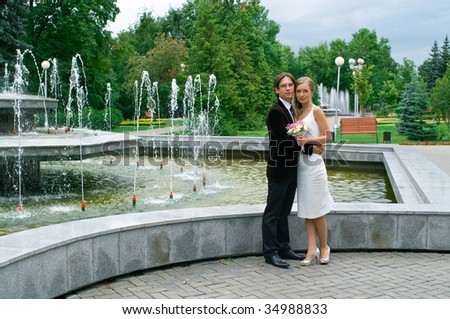 bride and groom against urban fountain. Summer landscape