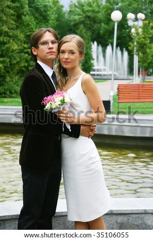 bride and groom against urban fountain. Summer landscape