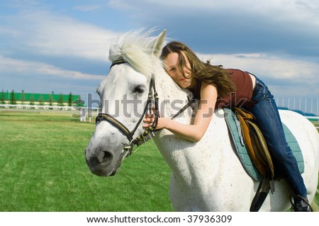 The young beautiful girl embraces a white horse