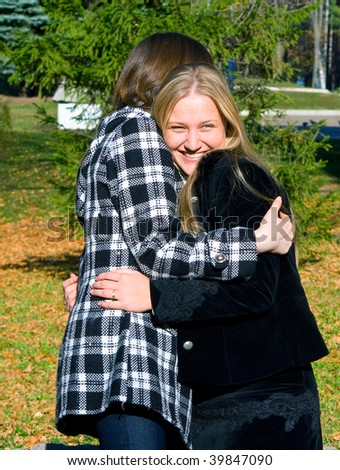 Two girls embrace at a meeting, rejoicing each other