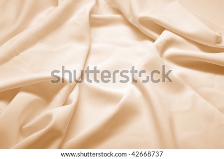 Abstract background, beige silk fabric with waves. Shallow DOF