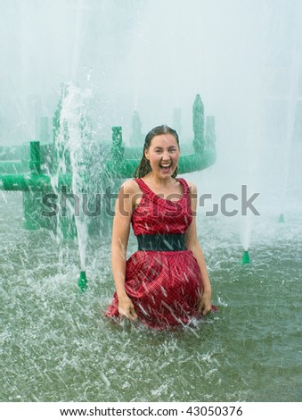 stock photo The young laughing girl in wet clothes in a city fountain