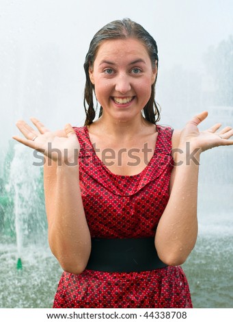 The young laughing girl in wet clothes in a city fountain