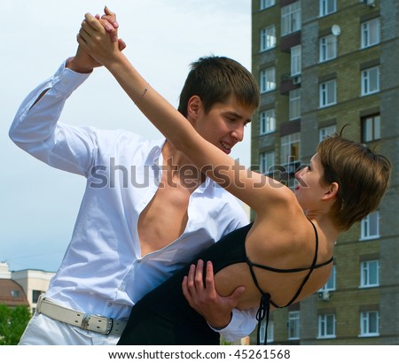 young couple dancing Latino dance against urban landscape