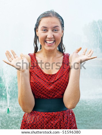 The young laughing girl in wet clothes in a city fountain