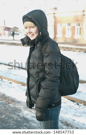 The girl at the station waiting the train against winter