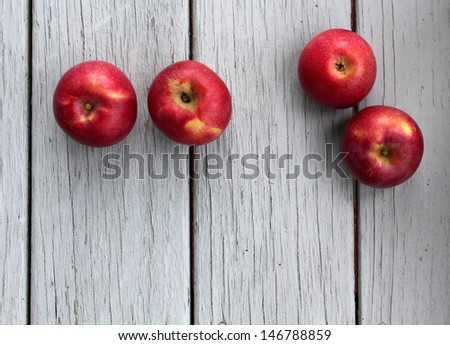 Four red crisp apples on gray boards, welcoming the Fall season to the countryside.