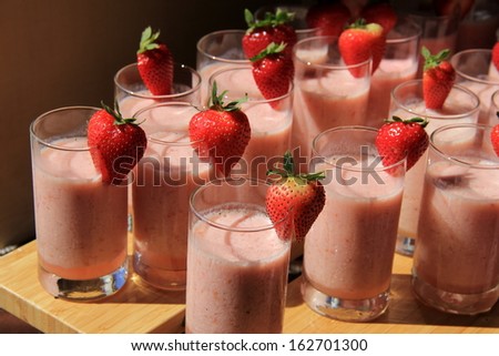 Tall glasses filled with delicious strawberry smoothies on buffet table at restaurant, tempting guests to choose something healthy for breakfast.