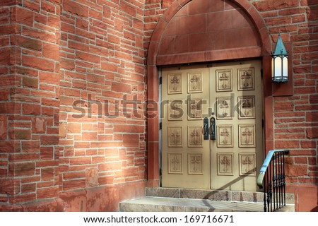 Hand carved wood doors with inlay of crosses on doors of brick and stone church.