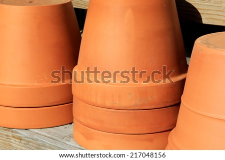 Stacks of terra cotta planters on long wooden table at local nursery, inviting shoppers to buy for planting flowers in them at home.