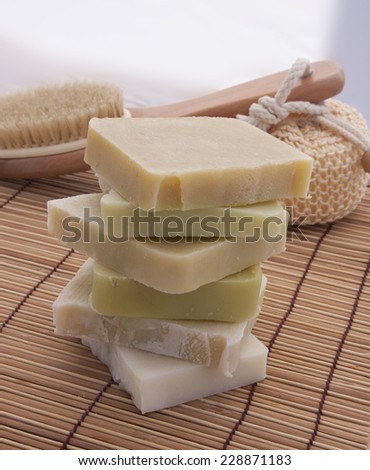 Green and white handmade soap on a bamboo background with bath supplies